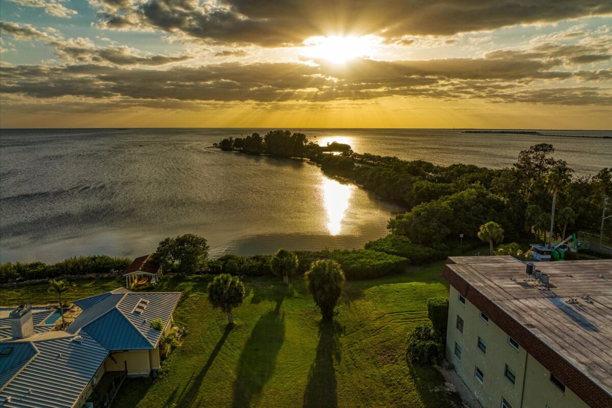 Sunset over calm coastal landscape – A picturesque sunset casting warm colors over a serene coastal area with lush greenery and distant islands.